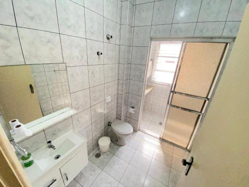 een badkamer met een toilet, een wastafel en een spiegel bij Pé na Areia Praia da Guilhermina IV in Praia Grande