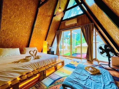 a bedroom with a bed and a large window at Bridge Hill Cafe Glamping in Khao Sok