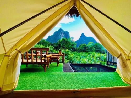 a tent with two benches and a view of the mountains at Bridge Hill Cafe Glamping in Khao Sok