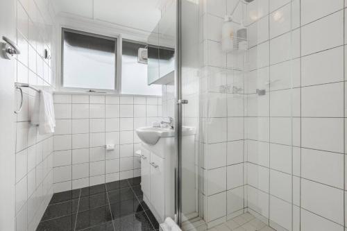 y baño de azulejos blancos con ducha y lavamanos. en Bright and Modern Space with a Balcony and Parking, en Melbourne