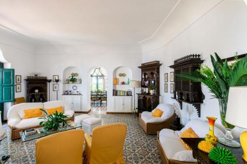 uma sala de estar com mobiliário branco e cadeiras amarelas em Villa Ginestra by Elite Villas em Capri