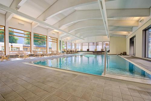 ein großer Pool mit Stühlen in einem Gebäude in der Unterkunft Schweizerhof Ferienwohnungen Lenzerheide 3 in Lenzerheide
