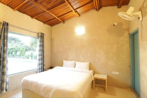 a bedroom with a white bed and a window at Brahmaputra cafe and resort in Bhundsi