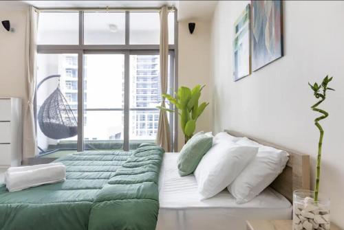 Un dormitorio con una cama con sábanas verdes y una ventana en 50% OFF Summer Offert, Nice w/ Balcony & Pool View en Dubái
