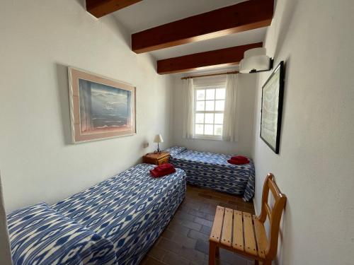 een slaapkamer met 2 bedden, een stoel en een raam bij ES CASTELL 1 by SOM Menorca in Fornells