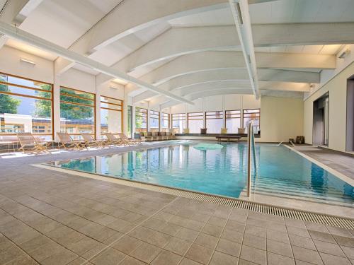 una gran piscina con sillas en un edificio en Schweizerhof Ferienwohnungen Lenzerheide 5 en Lenzerheide
