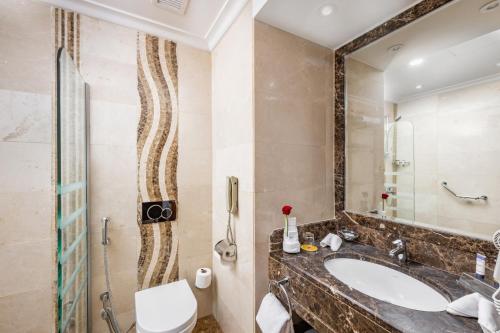 a bathroom with a sink and a toilet and a mirror at Elaf Kinda Hotel in Makkah