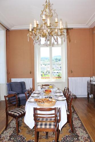 une salle à manger avec une table, des chaises et un lustre dans l'établissement La Belle Maison, à Eymoutiers