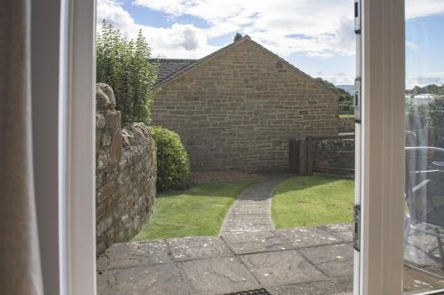 an open door to a yard with a brick building at Penhill in Redmire