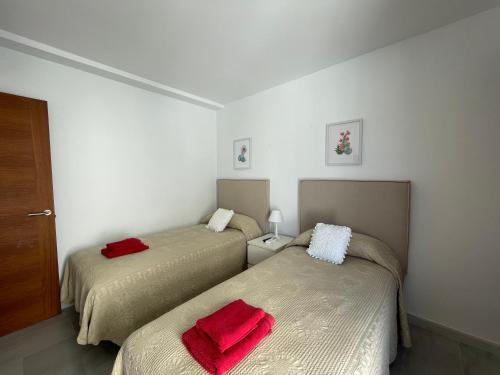 Dos camas en una habitación con toallas rojas. en BAHIA 28 by SOM Menorca en Fornells