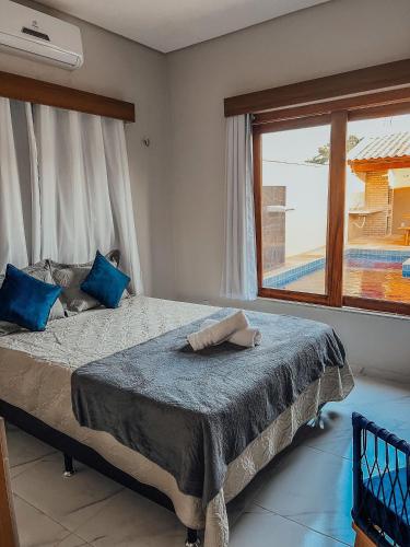 ein Schlafzimmer mit einem Bett mit blauen Kissen und einem Fenster in der Unterkunft Chill House Praia do Preá-CE in Prea