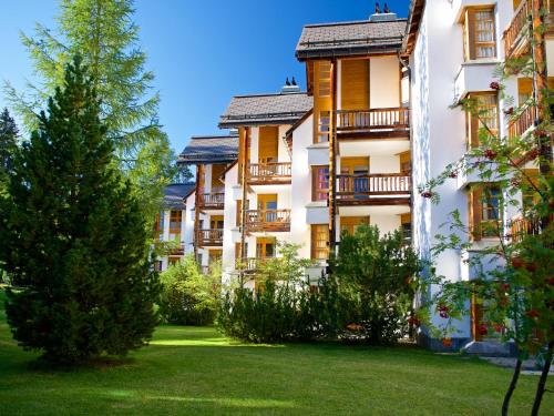 a row of apartment buildings with a green yard at Schweizerhof Ferienwohnungen Lenzerheide 6 in Lenzerheide