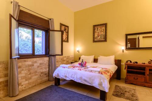 1 dormitorio con cama, ventana y espejo en My Place in the Colony, en Zikhron Ya‘aqov