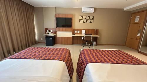 a hotel room with two beds and a tv at Jade Hotel Brasília in Brasilia