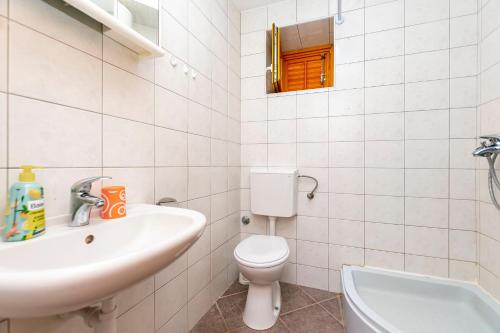 a white bathroom with a sink and a toilet at House Ante in Vinišće