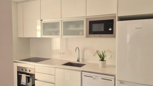 a white kitchen with a sink and a microwave at Afonso Galo Guest Apartments IV in Almada