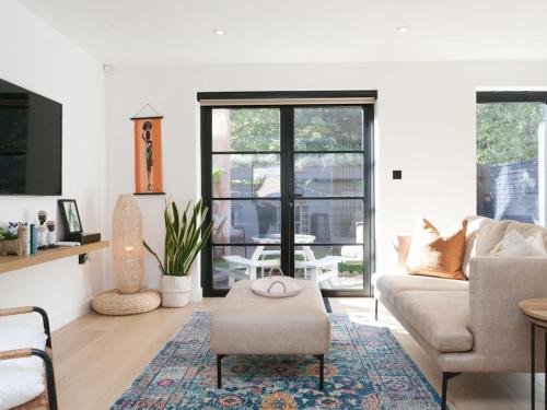 ein Wohnzimmer mit einem Sofa und einem Tisch in der Unterkunft Pass the Keys - Beautiful designer Maisonette with Garden and BBQ in London