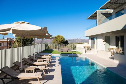 a swimming pool with chairs and an umbrella next to a building at Heliades Residence in Kounoupidhianá