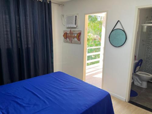 a bedroom with a blue bed and a bathroom at Bela casa em condominio de frente a cachoeira in Paraty