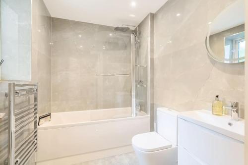 baño blanco con bañera, aseo y lavamanos en The Solo Haven 20 Min to Central, en Londres