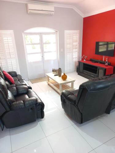 a living room with two leather chairs and a tv at Caribbeans Estates Villa 45 Calypso Drive in Port Edward