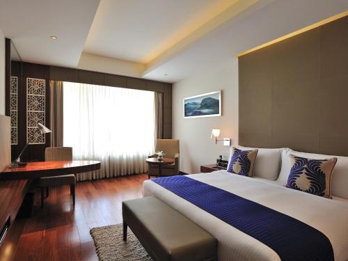 a hotel room with a large bed and a desk at The Anya Hotel-Golf Course Road in Gurgaon