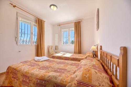 a bedroom with two beds and two windows at Villa Casita - PlusHolidays in Calpe