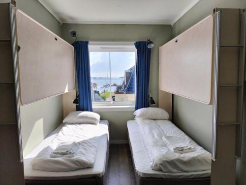Duas camas num pequeno quarto com uma janela em Sjøgløtt Gjestgiveri em Kristiansand