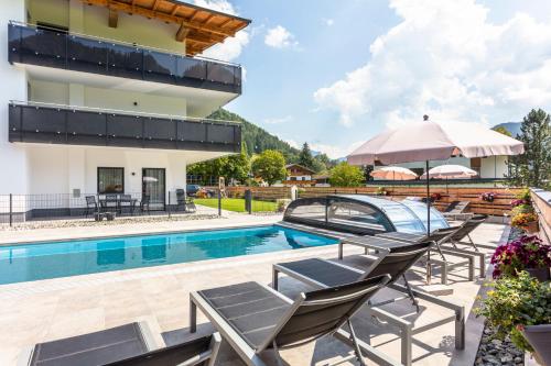 a villa with a swimming pool and lounge chairs at Kaiser Apart Walchsee in Walchsee