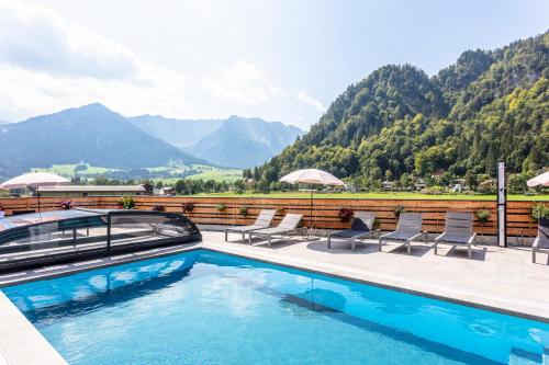 a swimming pool with chairs and a view of mountains at Kaiser Apart Walchsee in Walchsee