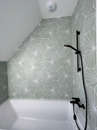 La salle de bains est pourvue d'une douche et d'un mur géométrique. dans l'établissement Villa neuve contemporaine avec piscine, à Fouesnant