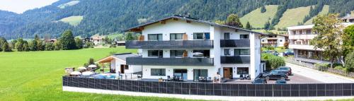a large white house on a hill with a green field at Kaiser Apart Walchsee in Walchsee