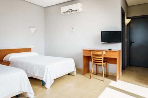 a room with two beds and a desk and a television at AS Chucena in Chucena