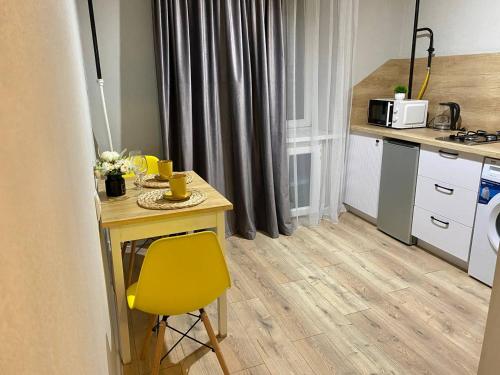 a kitchen with a table and a yellow chair at 1-комнатная квартира в районе Космос in Aktobe