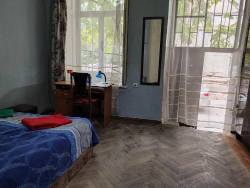 a bedroom with a bed and a desk and windows at Jessi on Marjanishvili in Tbilisi City