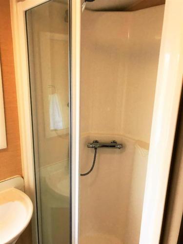 a shower with a glass door next to a sink at Newquay Bay Porth Caravan - 8 Berth in Newquay