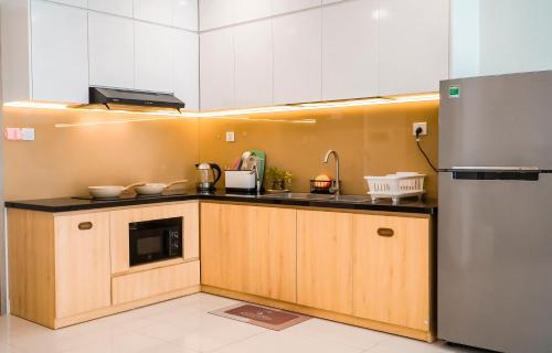 - une cuisine avec des placards en bois et un réfrigérateur dans l'établissement Vinhomes Grand Park - COZIroom, à Gò Công