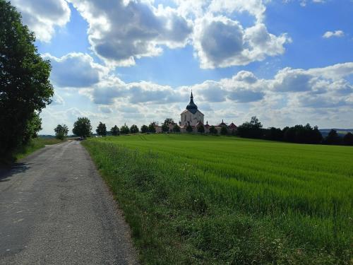 a church in the middle of a field with a road at Chalupa u Mikeše in Žďár nad Sázavou