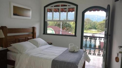 a bedroom with a bed and a large window at Pousada Encanto de Tiradentes in Tiradentes