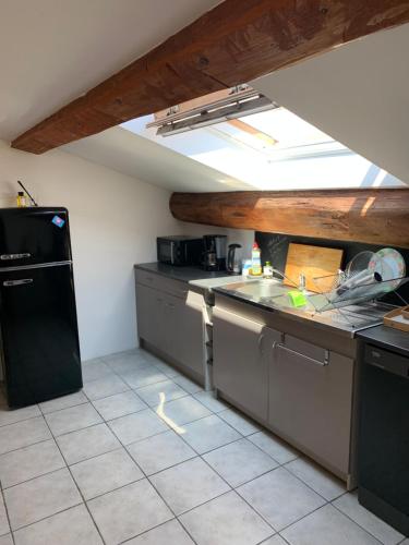 een keuken met een wastafel en een zwarte koelkast bij Appartement 2 pièces, vue Mont Saint Clair in Sète