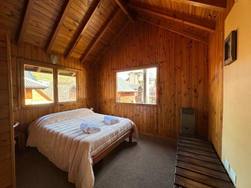 una camera con un letto in una cabina di legno di Casita Roca a San Martín de los Andes