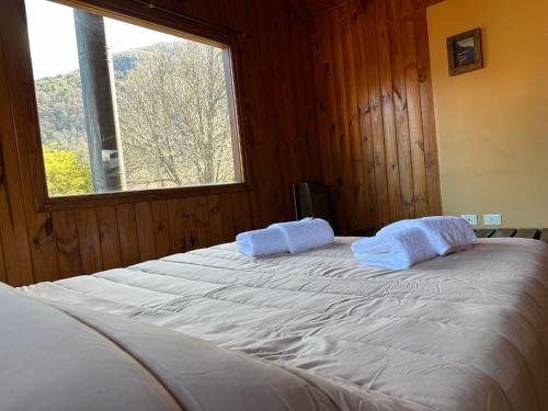una camera da letto con un grande letto bianco e una finestra di Casita Roca a San Martín de los Andes