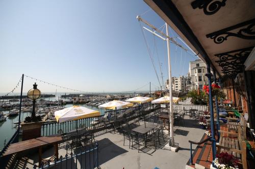 a balcony with tables and umbrellas and a harbor at Royal Temple Yacht Club in Ramsgate