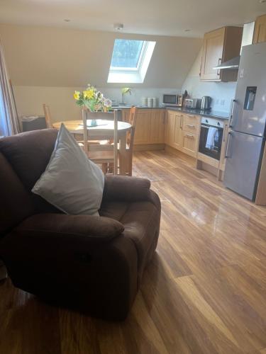 ein Wohnzimmer und eine Küche mit einem Sofa und einem Tisch in der Unterkunft Druid Apartment in Inverness