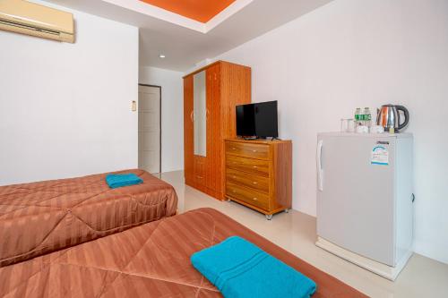 een slaapkamer met 2 bedden, een tv en een koelkast bij Nice to meat you Rooms in Patong Beach