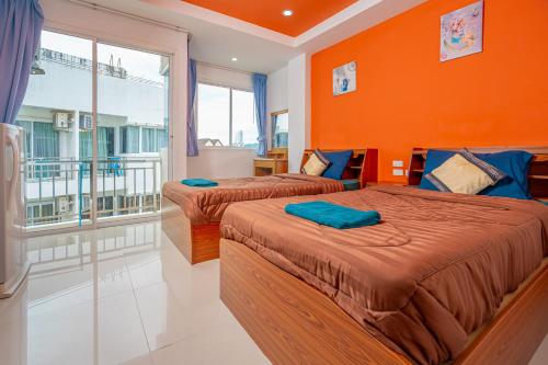 two beds in a room with an orange wall at Nice to meat you Rooms in Patong Beach