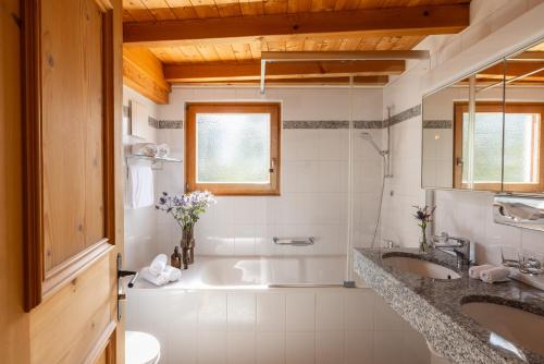 a bathroom with two sinks and a bath tub at Hotel Chesa Rosatsch - Home of Food in Celerina