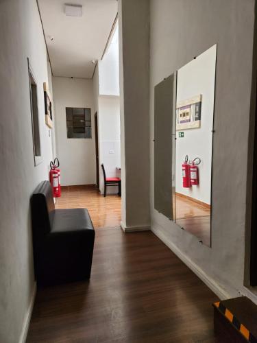a living room with a black chair and a mirror at Fujima Hostel in Sao Paulo
