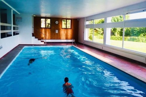 ein Schwimmbad in einem Haus mit einer Person darin in der Unterkunft Sunny 2 BR w large terrace, stunning views & pool in Crans-Montana