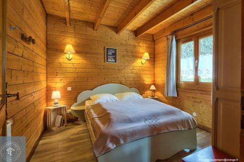 a bedroom with a bed in a wooden wall at Chalet Les Brimbelles avec Jacuzzi in Gérardmer